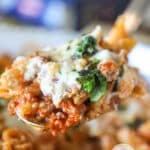 Serving spoon with a portion of baked pepperoni rigatoni on it.