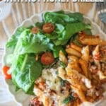 Baked pepperoni rigatoni with hot honey drizzle served on a plate with a side salad.