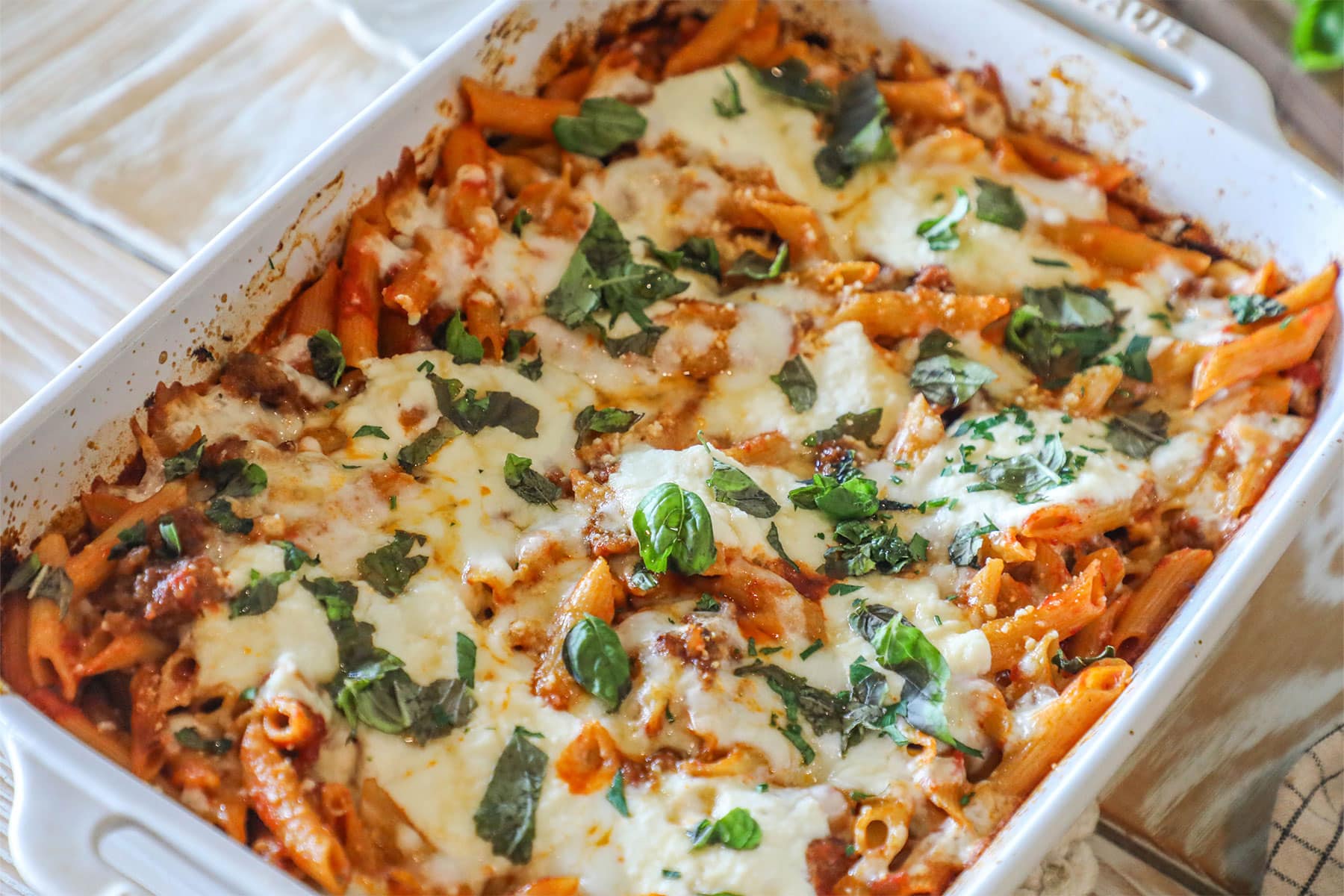 Baked pepperoni rigatoni with hot honey drizzle in a baking dish.
