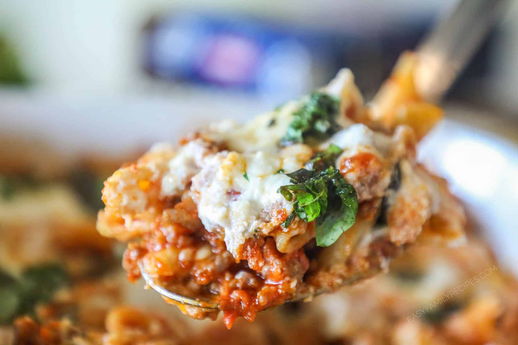 Serving spoon with a portion of baked pepperoni rigatoni on it.