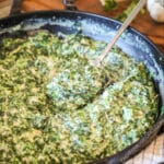 Skillet of easy creamed spinach with spoon.