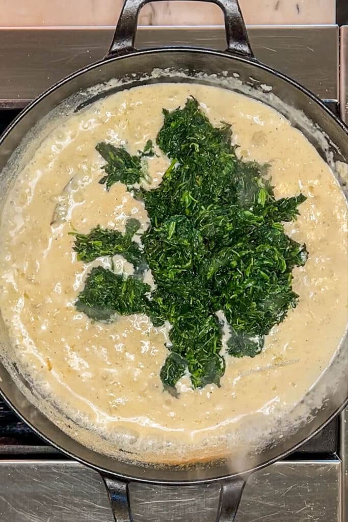 Spinach added to pan of cream sauce.