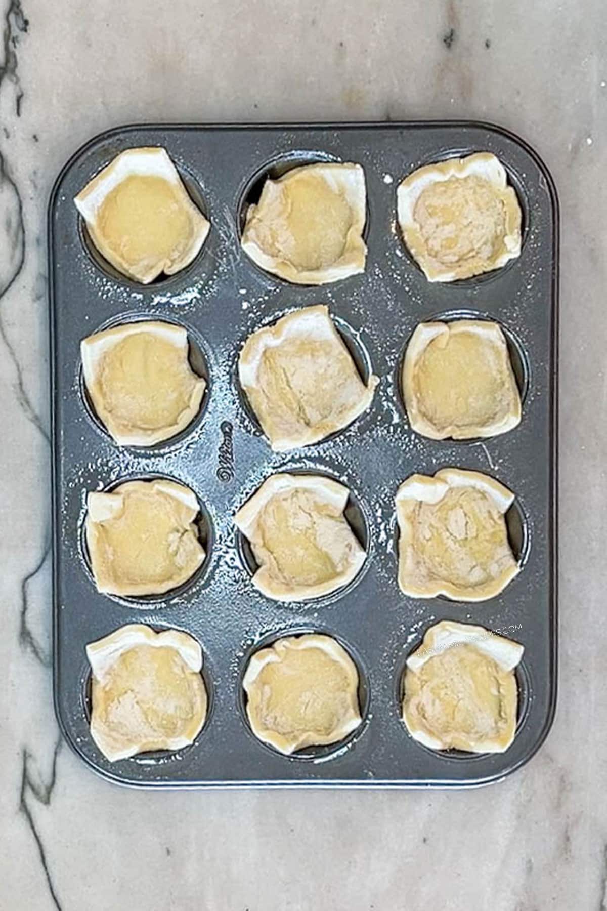 Step 3 for making Pear and Gorgonzola Puff Pastry Bites- put puff pastry into mini muffin tins