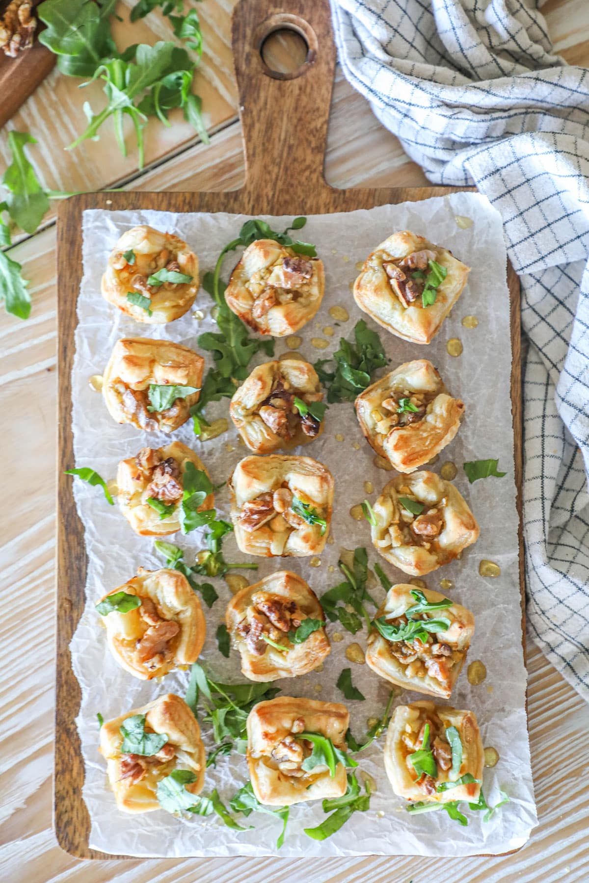 Step 6 for making Pear and Gorgonzola Puff Pastry Bites- bake, then sprinkle with chopped arugula and honey
