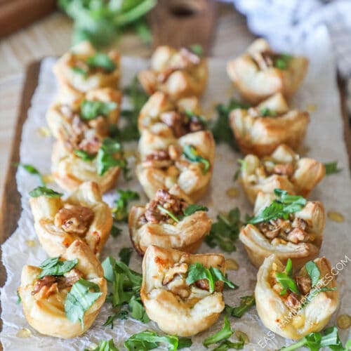 Pear and Gorgonzola Puff Pastry Bites with chopped arugula- on a wooden board- on a wooden background