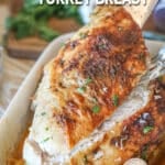 oven roasted turkey breast sliced and being lifted out of a pan.