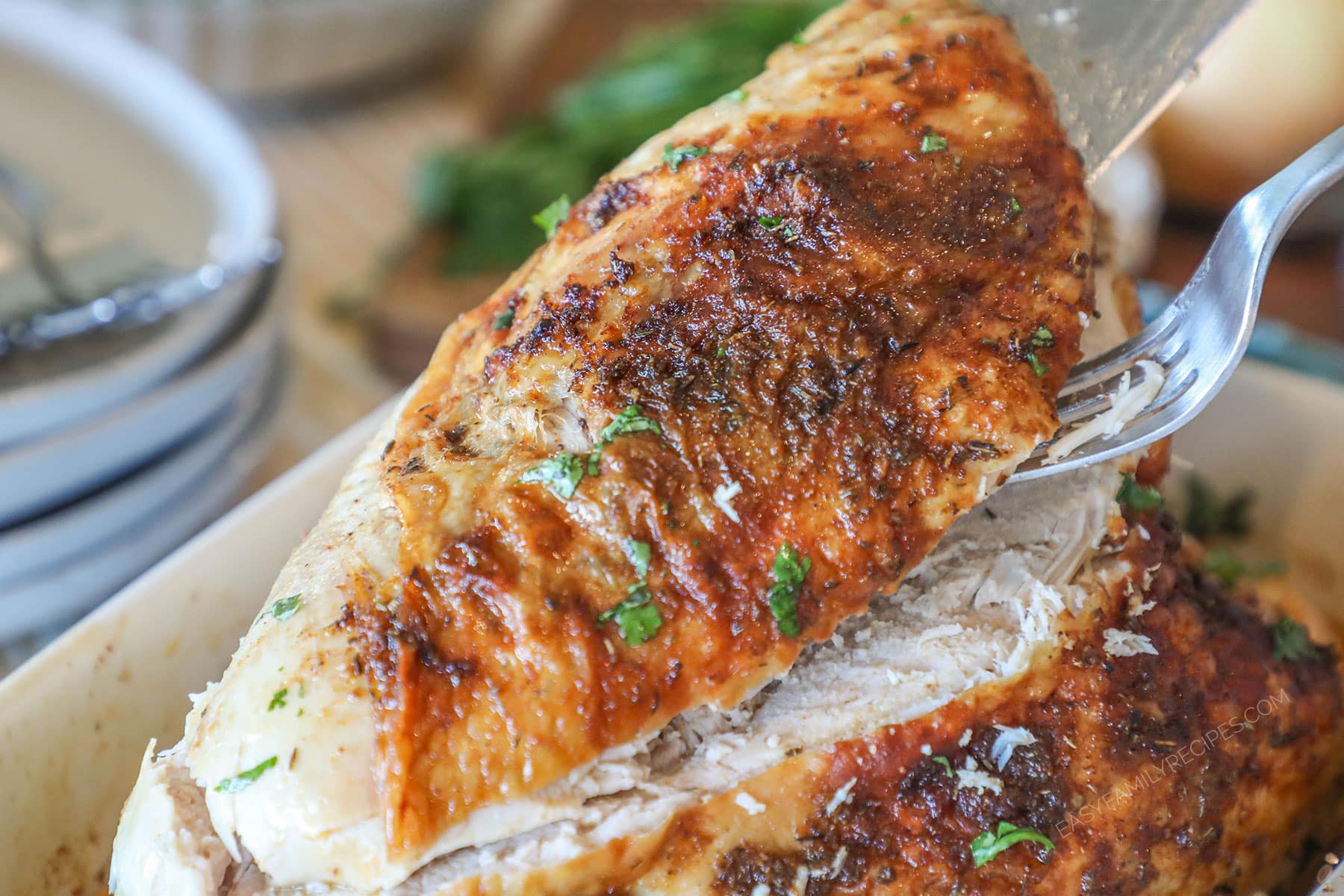 a slice of oven roasted turkey breast being lifted out of a baking dish.