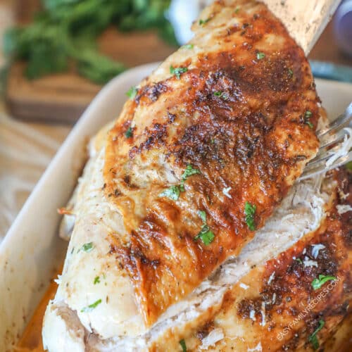 oven roasted turkey breast sliced and being lifted out of a pan.