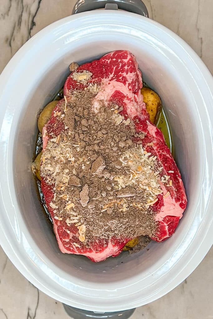 Seasoned beef chuck roast in slow cooker for beef manhattan.
