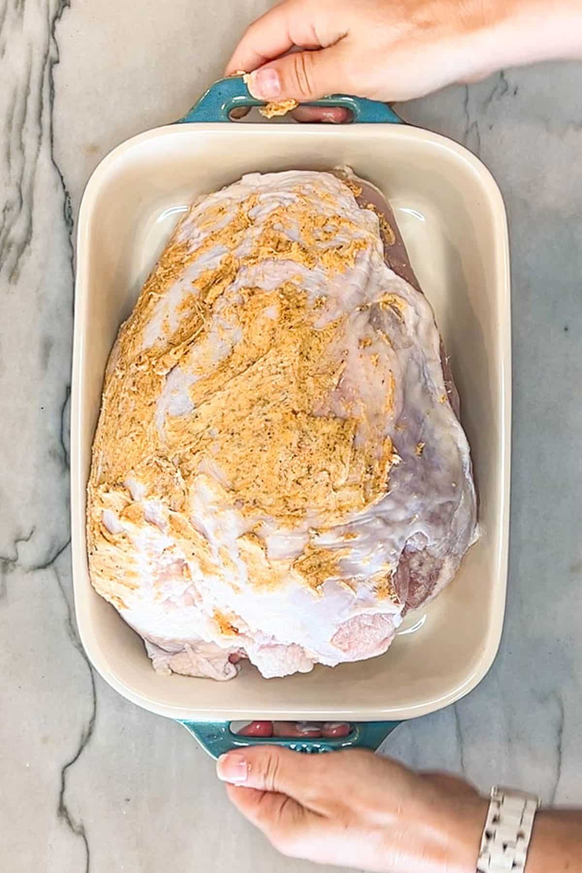 seasoned and buttered turkey in a baking dish.