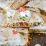 Sheet pan crunch wrap supremes stacked on pan with sour cream on top.