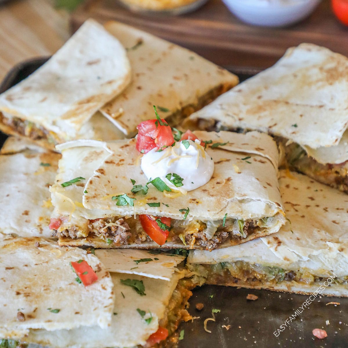 Sheet pan crunch wrap supremes stacked on pan.