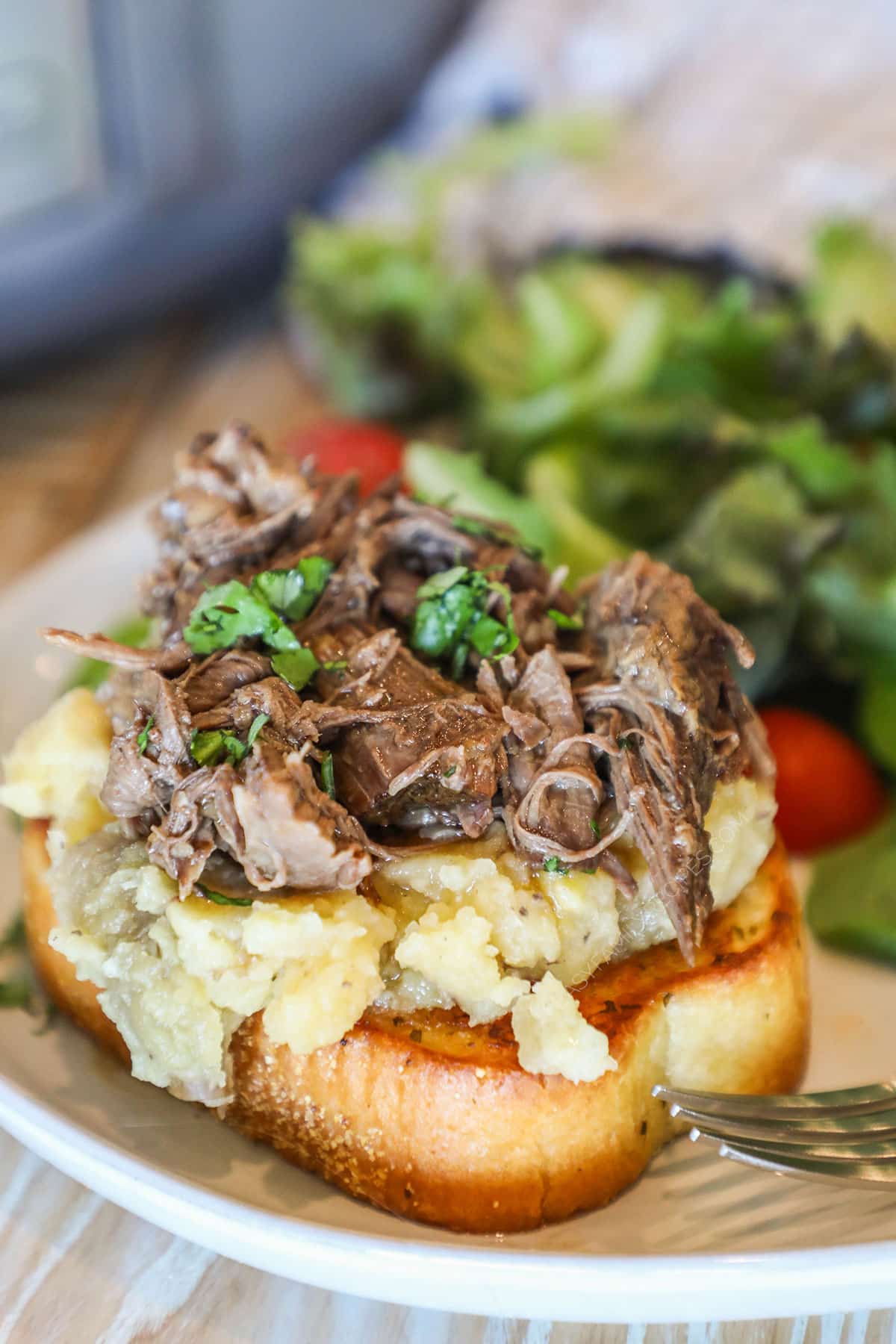 Crockpot beef manhattan on plate with salad.